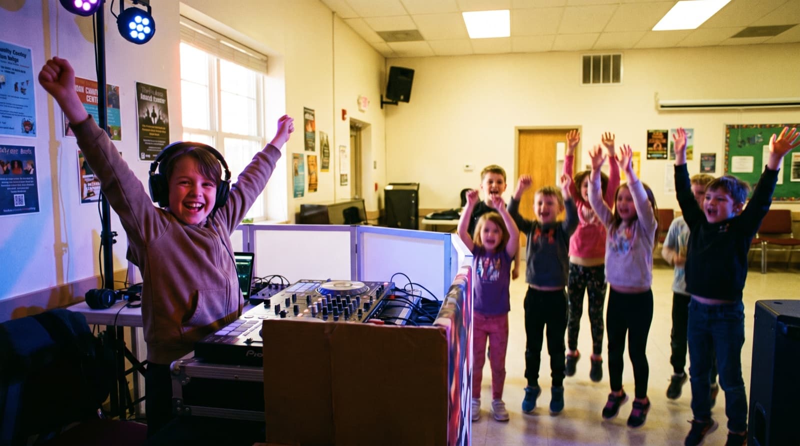 Kind feiert als DJ beim Kindergeburtstag, andere Kinder jubeln davor